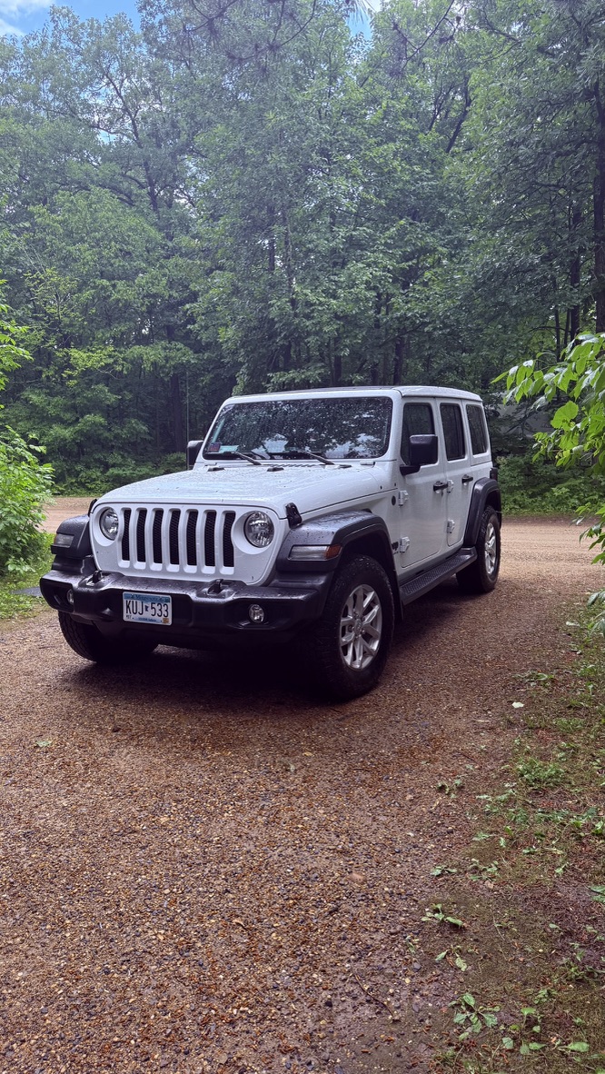 Our white Jeep Wrangler, the Dog House, parked among the trees