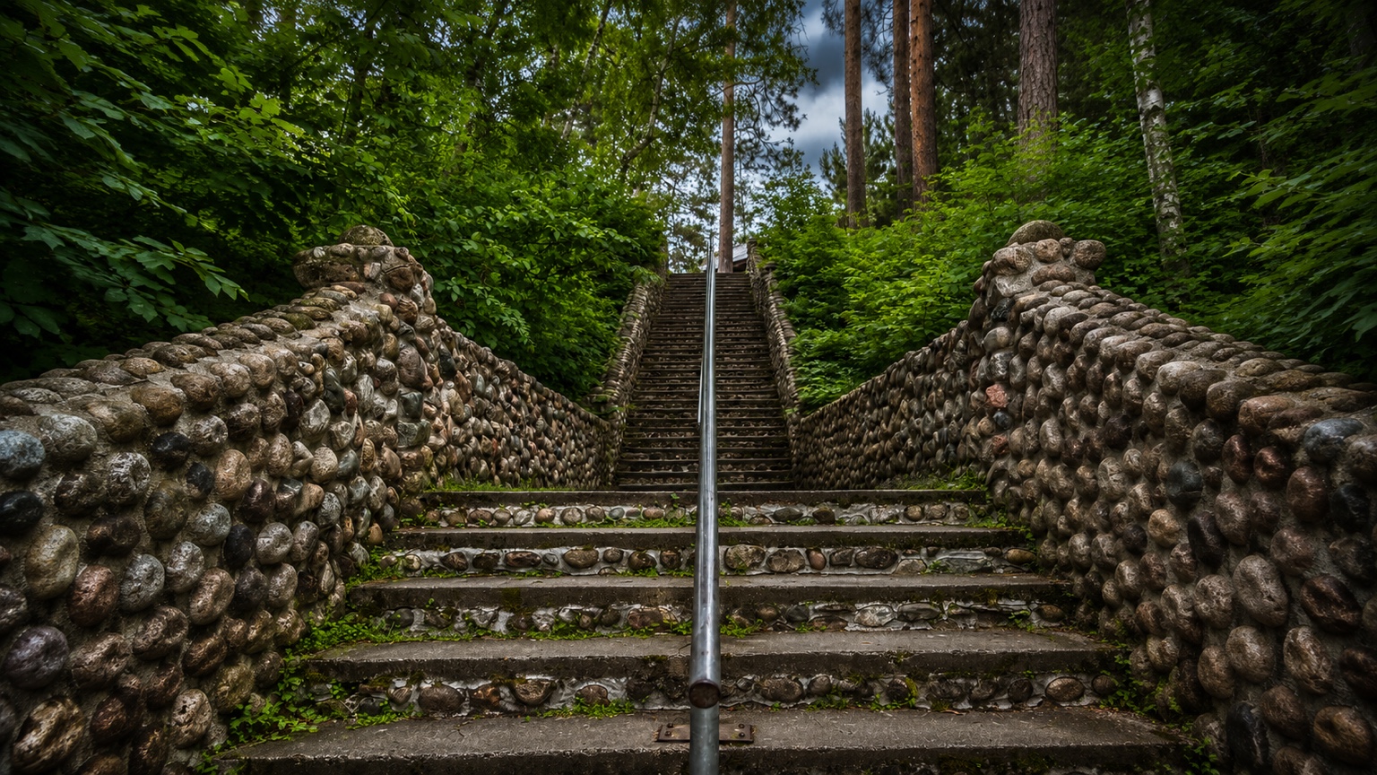 Stone steps and rounded stone walls rising into the green woodland